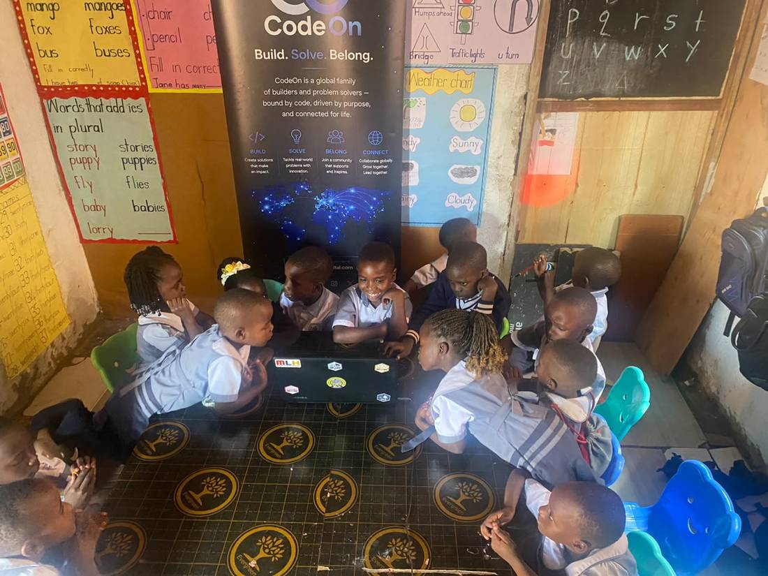 Young students gathered around a laptop with the CodeOn banner