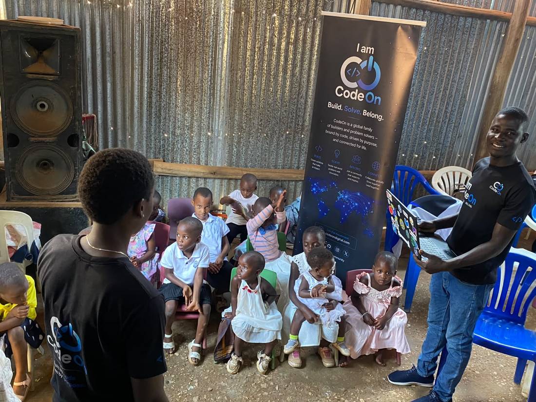 A CodeOn volunteer holding a laptop for young students